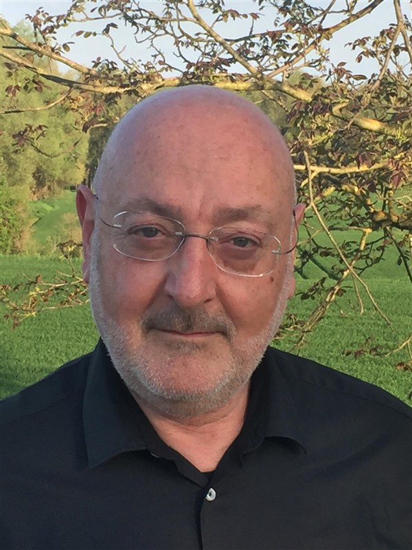 Giacomo Mauro D'Ariano standing in front of a dark background